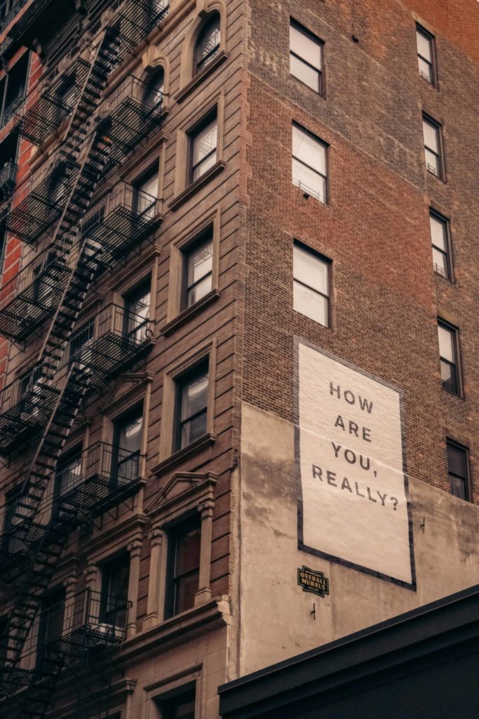 Brick building with billboard that reads how are you, really