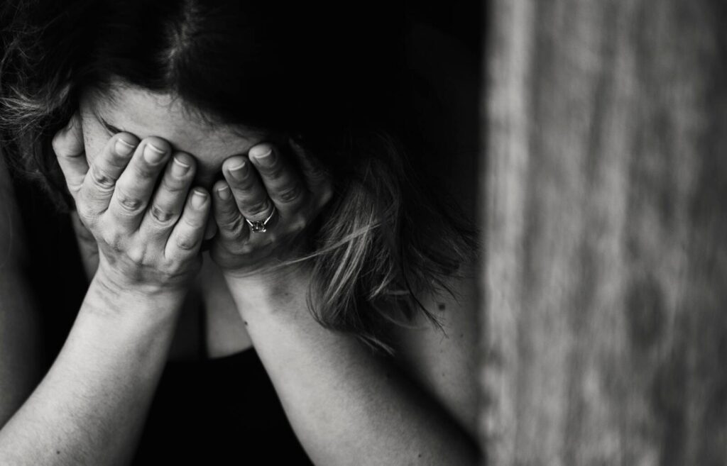 Girl covering her face with her hands to cover a stressed facial expression.