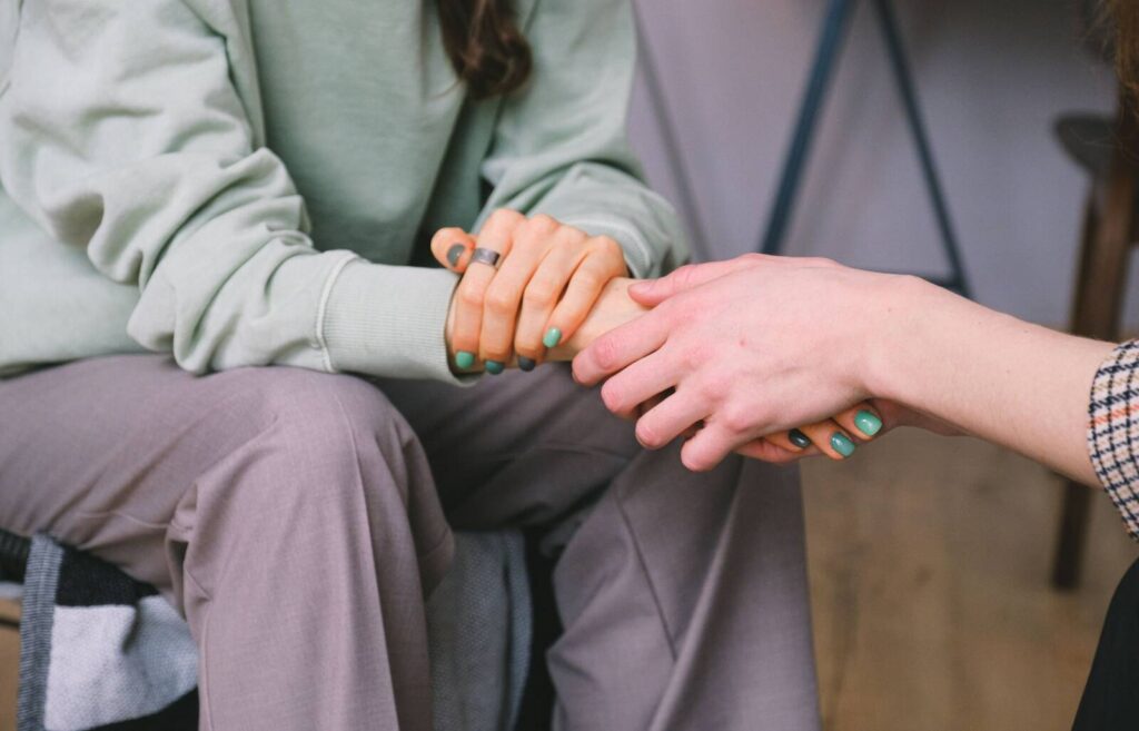 A close up of two people holding hands during a counseling session