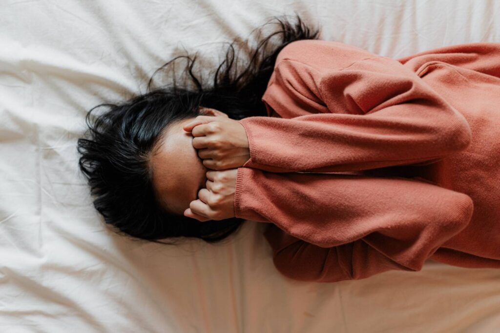 Girl laying in bed with anxiety. Girl covering her eyes and laying in bed. 