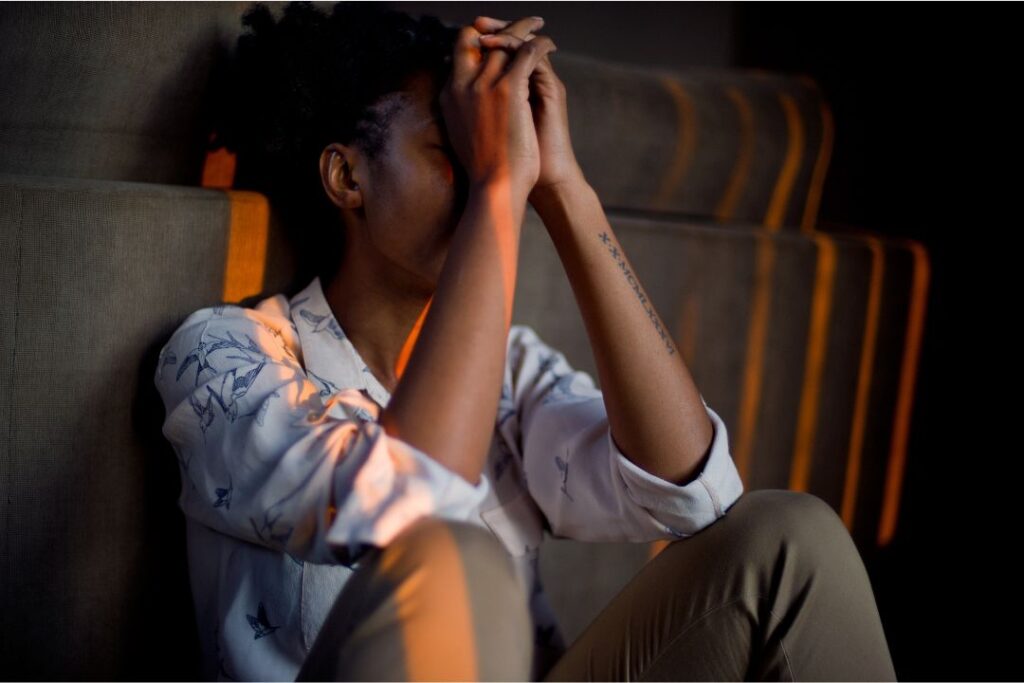 Woman sitting helplessly with hands covering her face.